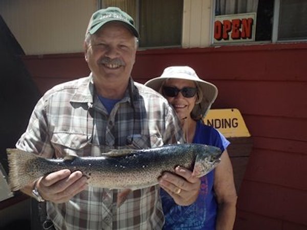 A man on a boat holding up his stringer with a caught fish, ca