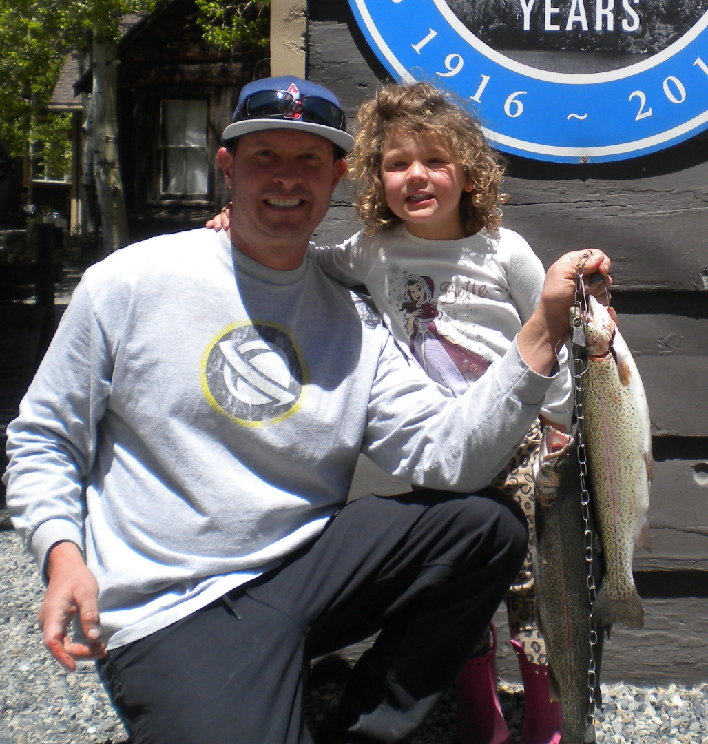 A man on a boat holding up his stringer with a caught fish, ca